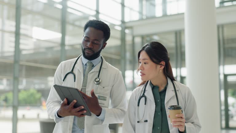 Walking, tablet and team of doctors in hospital in discussion for medical research, diagnosis or treatment. Professional, coffee and surgeon with healthcare worker on digital technology in clinic.